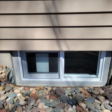 Replacement basement windows installed on gray siding home exterior — Twin Cities Metro MN