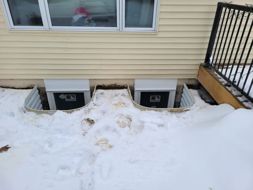 Two metal egress wells installed in winter