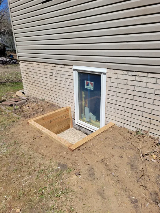 Timber well egress window installation gray siding